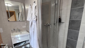 A modern bathroom with a glass-enclosed shower, a white sink, and a mirror. - Comfortable double room in the historic town center of Heidenheim (Heidenheim)