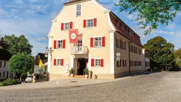 A two-story building with a red-tiled roof, a balcony with a wrought iron railing, and a sign indicating it is a restaurant. - Comfortable double room in the historic town center of Heidenheim (Heidenheim)