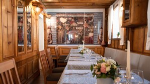 A long dining table set with chairs, a floral centerpiece, and a mural in the background. - Comfortable double room in the historic town center of Heidenheim (Heidenheim)