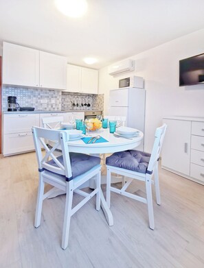 A modern kitchen with white cabinets, a dining table with chairs, and a refrigerator. - Green Retreat in Gornji Picudo (Umag)