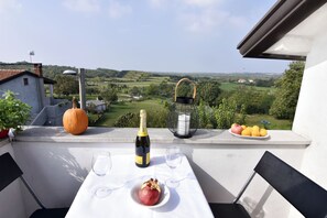 A balcony with a table set for two, a bottle of champagne, a pomegranate, and a plate of oranges. - Green Retreat in Gornji Picudo (Umag)