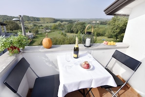 A balcony with a table set for two, a bottle of wine, a pomegranate, and a lantern. - Green Retreat in Gornji Picudo (Umag)