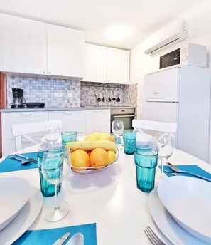 A modern kitchen with white cabinets, a tiled backsplash, and a dining table set with plates, cutlery, and a fruit bowl. - Green Retreat in Gornji Picudo (Umag)
