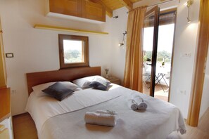 A bedroom with a bed, pillows, a window, a nightstand, a towel, and a balcony door. - Green Retreat in Gornji Picudo (Umag)