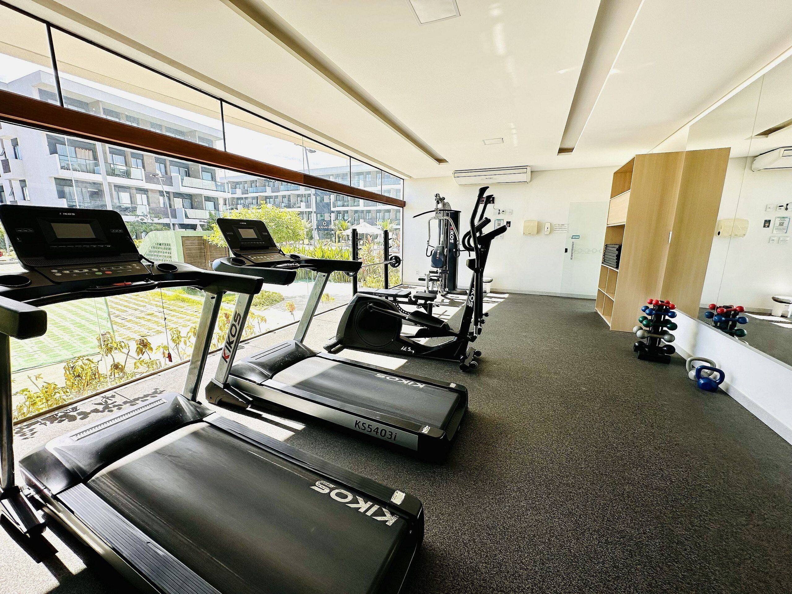 Une salle de sport équipée de tapis de course, d’un ordinateur portable posé sur un banc et de matériel d’exercice.