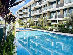 Un hôtel moderne doté d’une piscine, d’un espace extérieur aménagé et d’une végétation luxuriante.