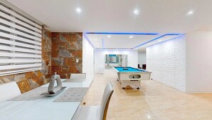 A modern room with a pool table, a seating area, and a stone accent wall. - Modern 3BR Apt  AC + Comfort & Style (Trujillo Alto)