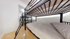 A bunk bed room with a metal frame, a staircase, and a tiled floor. - Modern 3BR Apt  AC + Comfort & Style (Trujillo Alto)