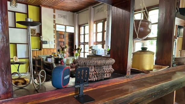 Une pièce avec un comptoir en bois, un panier tressé, un haut-parleur et un pot suspendu.