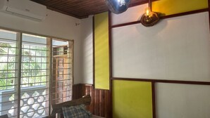 Une pièce avec un lit, une fenêtre donnant sur un beau paysage, un luminaire suspendu et un mur orné d’un panneau jaune.