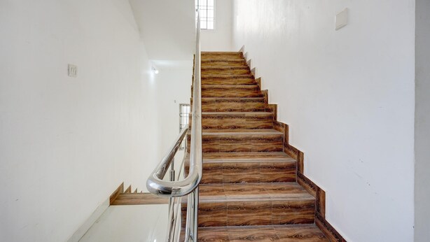 Una escalera con escalones de madera y barandilla de metal, que conduce a un rellano con una ventana.