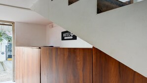 Zona de recepción de un hotel con un mostrador de madera y un letrero que indica que es un hotel de servicio empresarial.