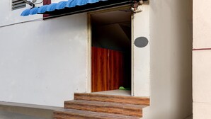 Unos escalones de madera conducen a una puerta con interior rojo.