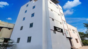 Un hotel de varios pisos con fachada blanca, múltiples ventanas y un letrero que indica que es un hotel.