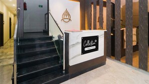 A hotel reception area with a staircase, a reception desk, and a wall-mounted logo. - Super Collection O Ranchi Station Road (Ranchi)