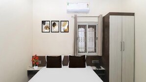 A bedroom with a bed, a wardrobe, a window with a view, and three framed pictures on the wall. - Super Collection O Ranchi Station Road (Ranchi)