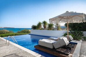 A pool with a view of the sea, a lounge area with a canopy, and a wooden deck. - The Sand Suites Residence (Crete)