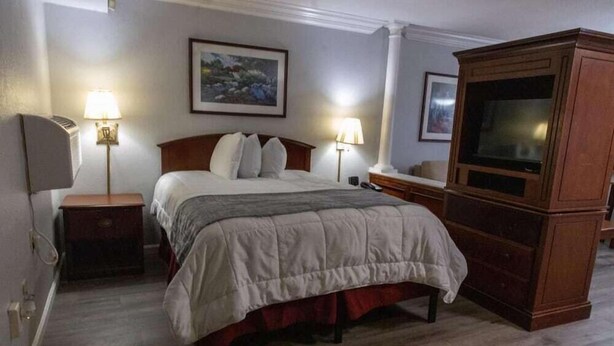 A hotel room with a bed, two bedside lamps, a television, and a framed picture on the wall. - Best Western Plus Atlantic City West Extended Stay And Suites (Pleasantville)