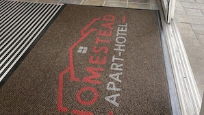 A hotel entrance with a reception desk, an ATM, and a doormat with the hotel name. - Best Western Plus Atlantic City West Extended Stay And Suites (Pleasantville)