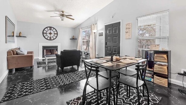 Una sala de estar moderna con chimenea, comedor y ventilador de techo.