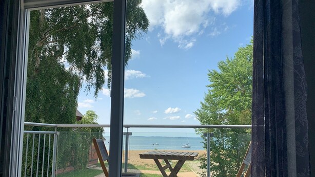 Un balcon donnant sur une plage, une table en bois et deux chaises.