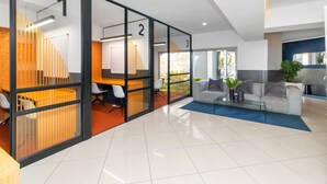 Ein moderner Büroarbeitsplatz mit Glastrennvorrichtungen, nummerierten Räumen, einem Sofa und einem Couchtisch.
