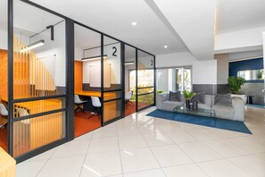 A modern office space with glass partitions, numbered rooms, a sofa, and a coffee table. - The Bolton Unit 130 (Johannesburg)