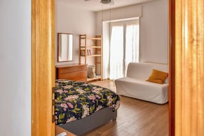 A bedroom with a bed, a dresser, a bookshelf, a white sofa with a yellow pillow, and a window with curtains. - Da Nonna Mena (Fossacesia)