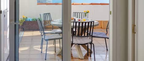 Un balcon avec une table et des chaises, une vue sur la mer et un bâtiment en arrière-plan.
