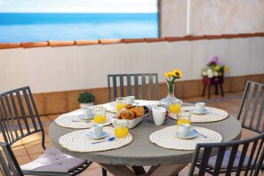 A round table with a breakfast setting, including croissants, orange juice, and coffee cups, overlooking a body of water. - Castle and Beach by Fidalsa (Alicante)