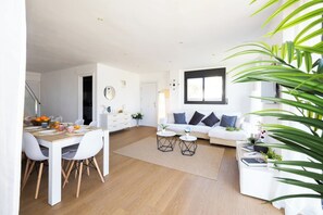 Un espacio moderno con comedor, un conjunto de sofás y un ventanal que proporciona luz natural.