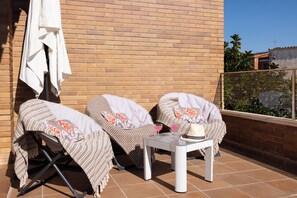 A patio with two covered chairs, a table, and a white umbrella.