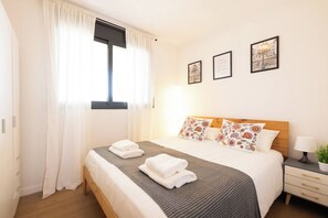 Une chambre d’hôtel avec un lit, une table de chevet, une lampe et une fenêtre avec des rideaux.