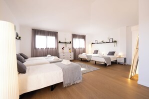 A modern hotel room with two beds, a bedside table, a nightstand, a lamp, and a large mirror.