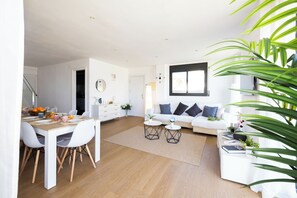 A modern living space with a dining area, a sofa set, and a coffee table.