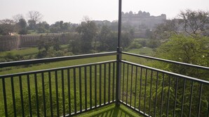 A balcony with a view of a castle and surrounding greenery. - The Ramayan (Orchha)