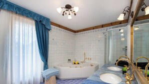 A bathroom with a large bathtub, two sinks, and a mirror.