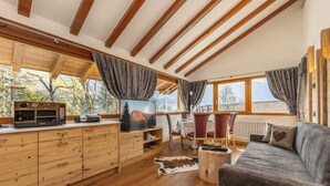 A wooden interior with a sofa, TV, wooden cabinets, and a dining area.
