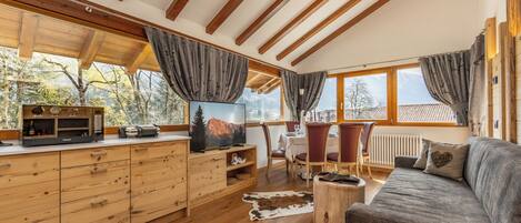A wooden interior with a sofa, TV, wooden cabinets, and a dining area.