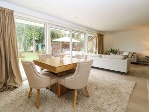 A modern living room with a dining area, large windows, and a view of the garden. - Three Ways (Diss)