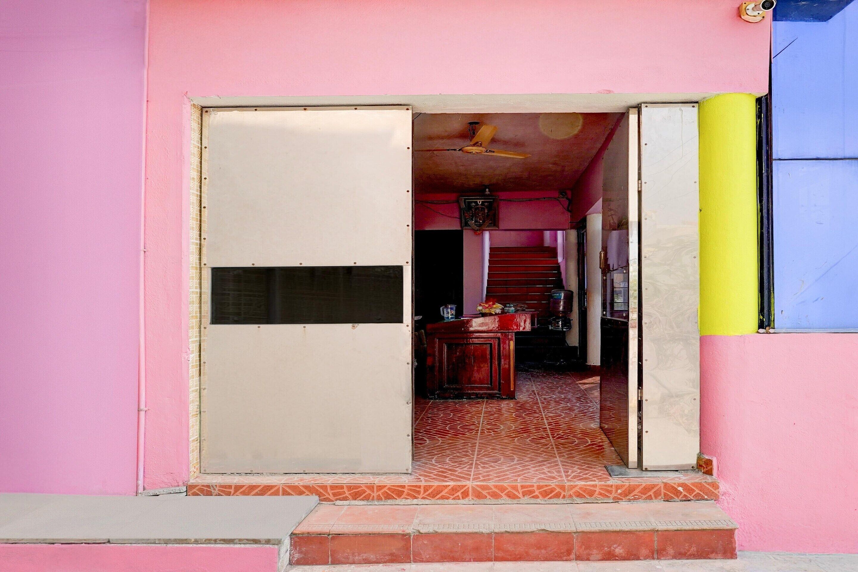 Un edificio rosa con piso de baldosas, una puerta y una escalera que lleva a un nivel superior.