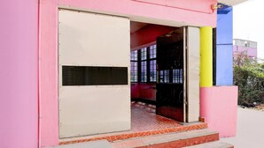 Un edificio rosa con una puerta y escalones que conducen al interior.