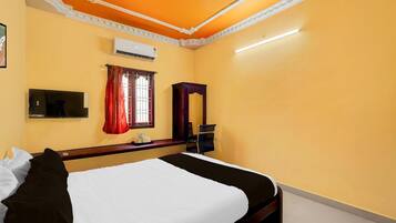 Habitación de hotel con cama, escritorio, aire acondicionado, ventana con cortinas y espejo.