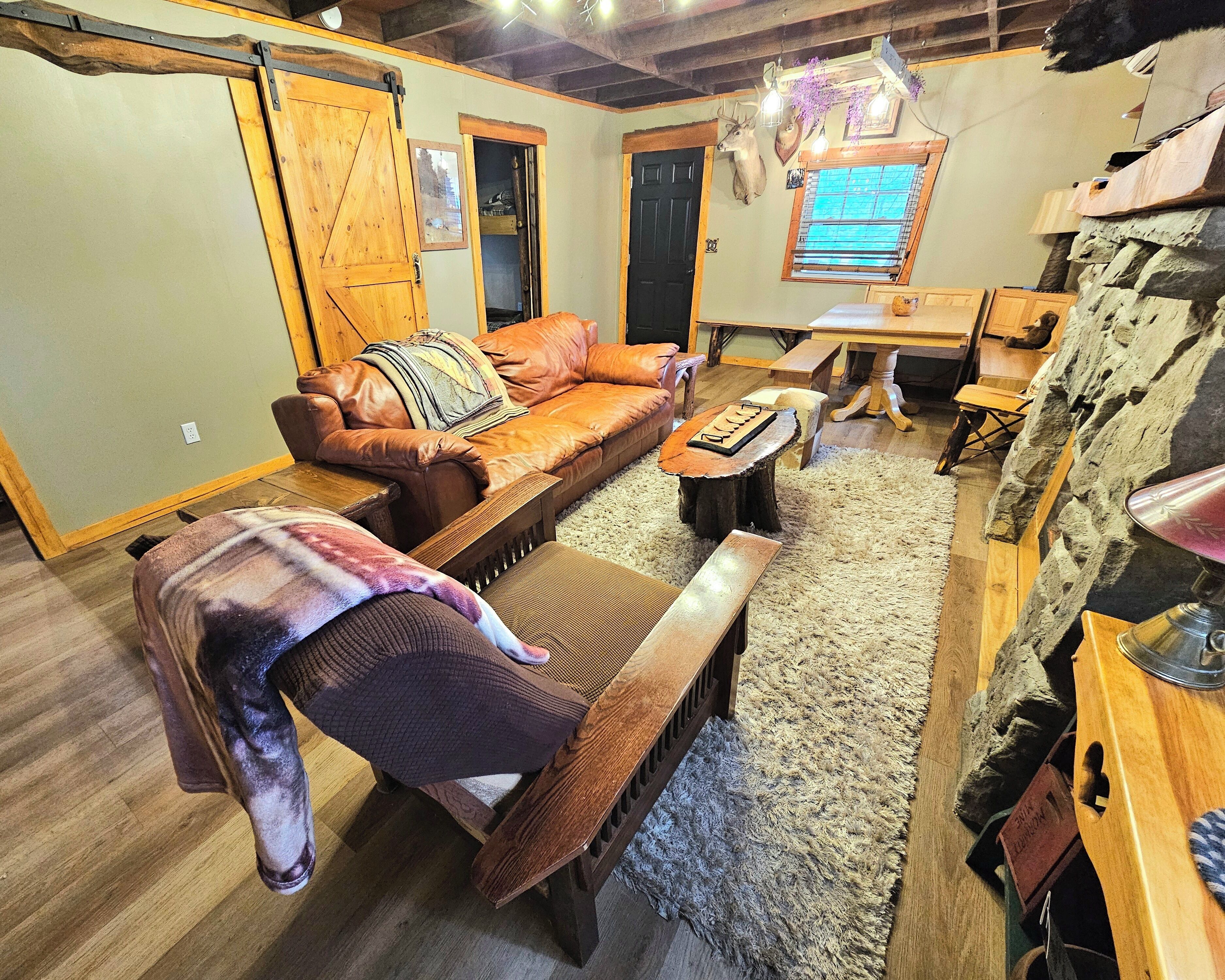 Un salon chaleureux avec un canapé en cuir, un banc en bois et un mur en pierre.