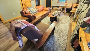 Un accogliente soggiorno con un divano in pelle, una panca di legno e un muro in pietra.