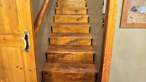 Una scala in legno conduce a un piano superiore, con vista sull'esterno attraverso una finestra.