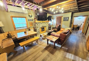 A cozy interior with a stone fireplace, wooden furniture, and a television mounted on the wall.