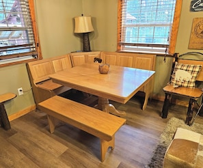 A dining area with a wooden table, benches, and a lamp.