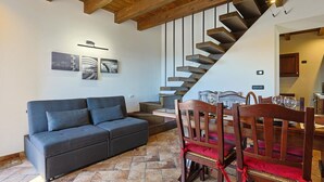 A modern living room with a sofa, dining table, chairs, and a staircase. - DAD House by Rentbeat (Fastello - Frazione Viterbo)