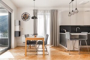 Eine moderne Küche mit Essbereich, großen Fenstern und Blick ins Freie.